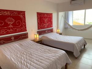 a bedroom with two beds and a red headboard at Praia da Ferradurinha Guest House in Búzios