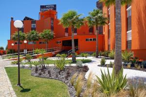 an orange building with palm trees in front of it at Zodiaco in Quarteira
