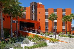 an orange building with palm trees in front of it at Zodiaco in Quarteira