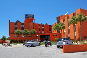 an orange building with cars parked in a parking lot at Zodiaco in Quarteira