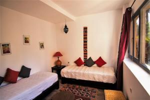 1 dormitorio con 2 camas y ventana en Maison d'Hôtes Kasbah Azul, en Agdz