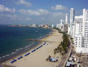 einen Strand mit Sonnenschirmen, Meer und Gebäuden in der Unterkunft Apartamento con Piscina Cartagena en el Laguito Bocagrande in Cartagena de Indias