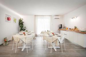 a kitchen with white tables and chairs in a room at B&B I Tre Olivi in Colà di Lazise