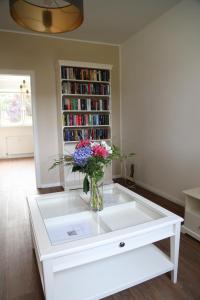 - une table basse blanche avec un vase de fleurs dans l'établissement goethe60, à Hohen Neuendorf