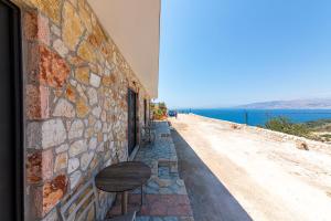 a stone wall with a table and a bench on a street at Santa Oliva Suites in Ksamil