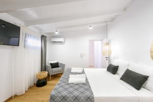 a white bedroom with a large bed and a chair at Matala Luxury Apartments in Matala
