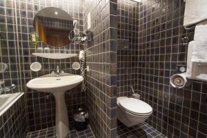 La salle de bains est pourvue de carrelage bleu, de toilettes et d'un lavabo. dans l'établissement Hotel Garni Römerhof, à Innsbruck