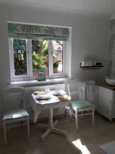 a white table and chairs in a kitchen with two windows at Darceys in the Yard in Hornsea
