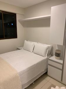 a white bed with white pillows and a window at Flats Mobiliados Zona Norte, Casa forte, recife, Aluguel por temporada Direto com o dono in Recife