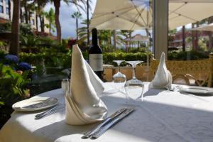 a white table with a bottle of wine and napkins at Hotel Puerto Palace in Puerto de la Cruz