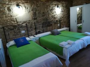 2 camas en una habitación con una pared de piedra en Hosteria Calixtino, en Palas de Rei 