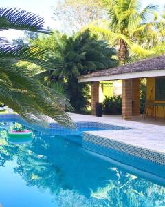 a swimming pool in front of a house with palm trees at Pousada Hostel Brazil Backpackers in Guarujá
