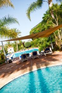 una piscina con tumbonas y palmeras en Luxe Villa Puerto Banus en Marbella
