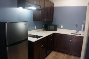 a kitchen with a black refrigerator and wooden cabinets at Texan Hotel in Corpus Christi
