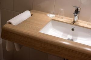 a sink in a bathroom with a towel hanging on the wall at Hotel Beysang in Châtenois