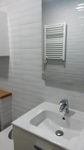 a white bathroom with a sink and a window at Apartamento con vistas a la catedral in Santiago de Compostela