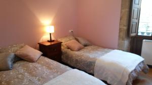 zwei Betten in einem Zimmer mit einer Lampe auf einem Tisch in der Unterkunft Apartamento con vistas a la catedral in Santiago de Compostela