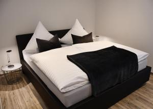 a bed with black and white sheets and pillows at Zum Anker in Simmerath