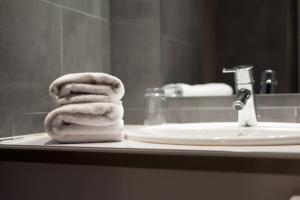 a stack of towels sitting on a bathroom sink at Hotel Beysang in Châtenois