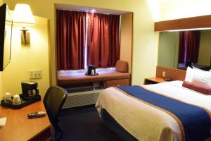 a hotel room with a bed and a desk and a window at Inn at the Finger Lakes in Auburn