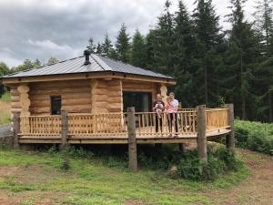 two women standing on a porch of a log cabin at Coed y Marchog Woodland Retreat in Hereford
