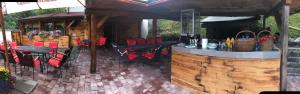 a patio with a bar with red chairs and tables at Penzión Holub in Tajov