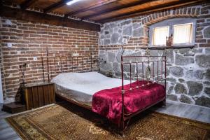 a bedroom with a metal bed in a brick wall at Guest House Antika in Prilep