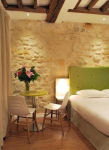 una camera con letto e tavolo con sedie di Hôtel De La Herse d'Or a Parigi