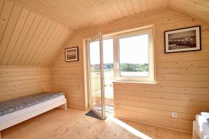 a sauna with a bed and a window at Piasek i Woda Domki in Grzybowo