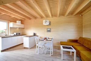 a kitchen and living room with a couch and a table at Piasek i Woda Domki in Grzybowo