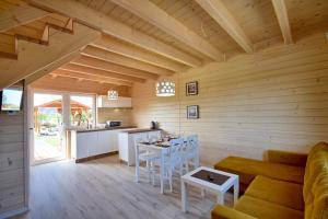 a kitchen and living room with a couch and a table at Piasek i Woda Domki in Grzybowo