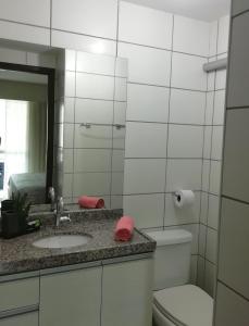 a bathroom with a sink and a toilet and a mirror at Beach Class Rosalux 707 in Fortaleza