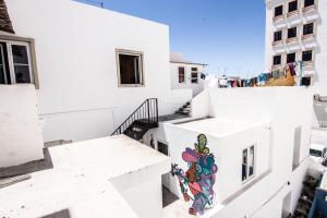 
a woman is standing in front of a white building at Hostellicious in Faro
