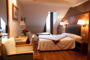 a hotel room with two beds and a desk at Alti Hôtel in Luchon