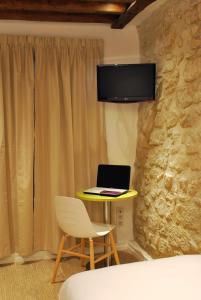 a living room with a chair and a tv at Hôtel De La Herse d'Or in Paris