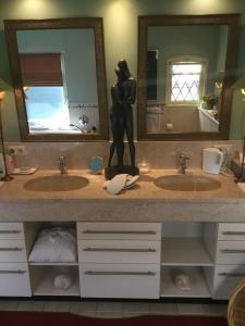 uma casa de banho com dois lavatórios e uma estátua de uma mulher no balcão em B&B lux Schijndel em Schijndel