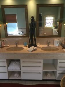 een badkamer met twee wastafels en een standbeeld van een vrouw op de toonbank bij B&B lux Schijndel in Schijndel