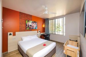 a bedroom with a bed with an orange wall at Gondwana City Green in Noumea +52 photos