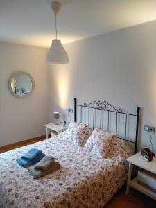 1 dormitorio con cama con colcha y almohadas en Apartamento Camiño dos Faros en Ponteceso