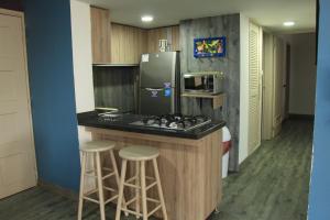 a kitchen with a stove and a refrigerator and stools at Apartamento de tres habitaciones en zona centro de San Andrés Islas - Edificio Comodoro 203 in San Andrés