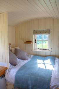 um quarto com uma cama azul num quarto com uma janela em Romantic secluded Shepherd Hut Hares Rest em Southwick