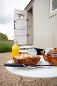 Romantic secluded Shepherd Hut Hares Rest في Southwick: طاولة مع رغيف خبز وزجاجة من عصير البرتقال