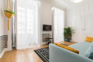 a white living room with a couch and a tv at Blue Tiles in City Center in Lisbon