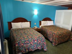 羅斯威爾的住宿－梅奧汽車旅館，酒店客房设有两张床和蓝色的墙壁。