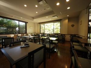 un comedor con mesas, sillas y ventanas en Hotel Route-Inn Kamisuwa, en Suwa