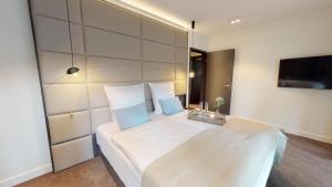 een slaapkamer met een groot wit bed met blauwe kussens bij White Pearl Apartment 0.06 in Timmendorfer Strand