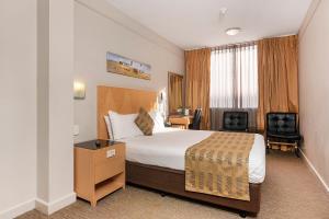 a hotel room with a bed and a desk at Quality Hotel Ambassador Perth in Perth
