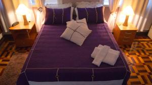 a large bed with purple sheets and pillows in a bedroom at Pousada Realiza in Cambuquira