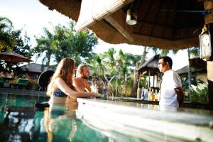 a group of people sitting at a bar in a swimming pool at Mara River Safari Lodge Bali in Keramas