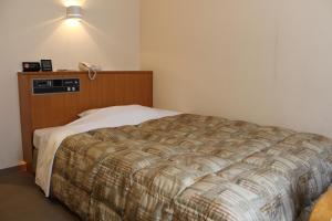 a bedroom with a bed and a phone on the wall at Hotel Tetora Makuhari Inagekaigan (Formerly Business Hotel Marine) in Chiba